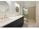 Bathroom with dual sinks, granite countertops, gold fixtures, and a glass enclosed shower at 718 W Trade St # 105, Charlotte, NC 28202