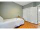 A simple bedroom with hardwood floors, a bed, closet, and a view into an adjacent bathroom at 7725 Whitmire Ln, Mint Hill, NC 28227