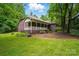 A rear view of a brick home featuring a covered porch and green lawn at 7725 Whitmire Ln, Mint Hill, NC 28227