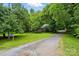 A long gravel driveway leading to a house surrounded by mature trees and lush greenery at 7725 Whitmire Ln, Mint Hill, NC 28227