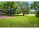 Beautifully maintained front yard with mature trees, lush green grass, and meticulously landscaped flower beds at 7725 Whitmire Ln, Mint Hill, NC 28227