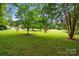 Spacious front yard showcasing lush green grass, mature trees, and a serene atmosphere at 7725 Whitmire Ln, Mint Hill, NC 28227