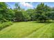 Expansive front yard featuring lush green grass, mature trees, and a charming view of the house in the background at 7725 Whitmire Ln, Mint Hill, NC 28227