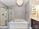 Bright bathroom boasts a soaking tub, glass shower, and modern vanity with dual sinks at 8218 Houston Ridge Rd, Charlotte, NC 28277