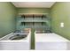Laundry room with a modern washer and dryer, shelves, and clean, green walls at 8624 Canter Post Dr, Charlotte, NC 28216