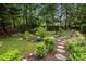 Beautifully landscaped backyard with a stone pathway, flower beds, and lush greenery at 10703 Back Ridge Rd, Charlotte, NC 28277