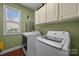 Bright laundry room with modern washer and dryer and overhead storage cabinets at 10703 Back Ridge Rd, Charlotte, NC 28277