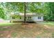Spacious backyard with green lawn and charming deck; shaded by a large, mature tree at 121 Jefferson Dr, Locust, NC 28097