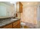 Functional bathroom with granite counter, wood cabinets, and shower with patterned curtain at 121 Jefferson Dr, Locust, NC 28097