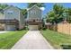 View of the backyard with a two-story home, green grass, and a concrete driveway leading to the garage at 12220 Huntersville Concord Rd, Huntersville, NC 28078