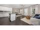 Open living room boasts dark wood floors, modern ceiling fan, and a kitchen island with barstool seating at 12220 Huntersville Concord Rd, Huntersville, NC 28078