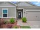 Charming front entrance with a well-manicured yard, complementary shrubs, and attached garage at 1344 Sweet Pea St, Monroe, NC 28110