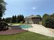A stunning backyard showcasing a kidney-shaped pool, lush greenery, and a screened-in porch at 14700 Old Vermillion Dr, Huntersville, NC 28078