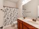 Well-lit bathroom features a double sink vanity with a shower-tub combo and decorative shower curtain at 14700 Old Vermillion Dr, Huntersville, NC 28078