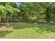 Backyard featuring a lush green lawn and a cozy fire pit surrounded by trees at 1713 Shamrock Dr, Charlotte, NC 28205