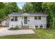 Charming white brick home featuring a beautifully landscaped front yard and a welcoming green front door at 1713 Shamrock Dr, Charlotte, NC 28205