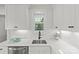 Bright kitchen features white cabinets, marble backsplash, stainless sink, and black faucet at 1713 Shamrock Dr, Charlotte, NC 28205