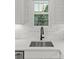 Close up view of a kitchen sink with white marble countertops and white tile backsplash at 1713 Shamrock Dr, Charlotte, NC 28205