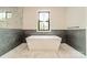 An elegant bathroom with a soaking tub, marble floors, tiled accent walls and natural light at 2412 Kingsbury Dr, Charlotte, NC 28205