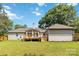 A view of the back of the property featuring a sunroom, back deck, and garage, all surrounded by a lush lawn at 3801 Rea Rd, Charlotte, NC 28226
