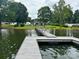 View from the dock to the home with a well manicured lawn, trees, and serene lake, creating a peaceful waterfront retreat at 4574 Ivy Run Ln, Denver, NC 28037