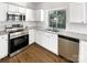 Well-lit kitchen with white cabinetry, stainless steel appliances, and hardwood floors at 6413 Fillian Ln, Charlotte, NC 28269