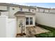 Exterior view of the back of a light colored townhouse, with a small patio and green grass at 7943 Mariners Pointe Cir, Denver, NC 28037