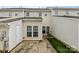 Exterior view of the back of a light colored townhouse, with a small patio and green grass at 7943 Mariners Pointe Cir, Denver, NC 28037