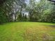 Large grassy backyard surrounded by lush trees at 1004 E 8Th Ave, Gastonia, NC 28054