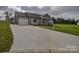 View of a wide concrete driveway leading to a light gray one-story house with an attached garage at 108 Devynne Ct, Salisbury, NC 28146