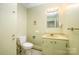 Bright bathroom with toilet, sink with custom cabinets, and a large mirror with Hollywood lighting at 1410 Patterson St, China Grove, NC 28023