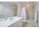 Bright bathroom featuring a single sink, white cabinetry, large mirror, and bathtub with a shower at 14652 Villalonga Ln, Charlotte, NC 28277