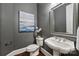 Stylish powder room featuring a pedestal sink, framed mirror, gray walls, wood floors, and decorative accents at 14652 Villalonga Ln, Charlotte, NC 28277