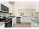Modern kitchen showcasing stainless steel appliances, granite counters, white cabinets, and an open view to the living area at 1518 Doran Ter, Richburg, SC 29729