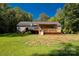 View of the rear exterior and spacious backyard featuring a deck, landscaped garden, and well-maintained lawn at 1738 Charlotte Hwy, Lancaster, SC 29720