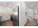 Modern kitchen with stainless steel appliances, white cabinetry, and a hallway leading to a room with a desk at 18679 Vineyard Point Ln, Cornelius, NC 28031