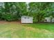 Backyard view of a well maintained storage shed amongst mature trees and lush green lawn at 211 Tyndale Ct, Waxhaw, NC 28173