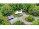 Aerial view of the property showcasing a mobile home, sheds, Quonset hut, graveled drive, and wooded surroundings at 2289 Mccloud St, Denver, NC 28037