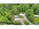 Wide aerial view of the property with a mobile home, sheds, a Quonset hut, graveled drive, and wooded surroundings at 2289 Mccloud St, Denver, NC 28037