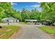 Wide exterior shot showcases the gravel driveway, home, and two outbuildings at 2289 Mccloud St, Denver, NC 28037