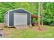 Exterior view of a grey storage building with a roll up door, side awning, and concrete ramp at 2289 Mccloud St, Denver, NC 28037