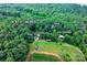 A scenic aerial view of a wooded 6.97-acre lot featuring a cabin, carport, sheds, and a tractor shed at 2951 Evergreen Trl, Vale, NC 28168