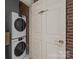 Stacked washer and dryer in the laundry area with brick accents at 310 Arlington Ave # 409, Charlotte, NC 28203