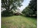 View of the backyard with a grassy area surrounded by mature trees and foliage at 3500 Blessing St, Charlotte, NC 28208