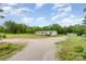 Wide shot of a tan single-story home with a gravel driveway and surrounding greenery and a shed at 4518 Logging Rd, Lancaster, SC 29720