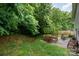 Lush backyard featuring a patio with wood furniture, a stone fire pit, and mature trees for privacy at 4837 Autumn Oak Dr, Charlotte, NC 28269