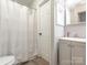 Bathroom with white wooden door, sink with gray cabinets, and patterned shower curtain at 8208 Cedar Glen Dr, Charlotte, NC 28212