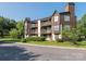 Attractive condo building with multiple balconies, manicured landscaping, and mature trees at 8208 Cedar Glen Dr, Charlotte, NC 28212