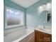 Bright bathroom with a large tub, vanity with cabinet, and large mirror at 9564 Kings Parade Blvd, Charlotte, NC 28273