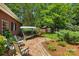 A brick patio with swing seating and manicured landscaping invites relaxation in this lush backyard setting at 102 Rosewood Ln, Locust, NC 28097